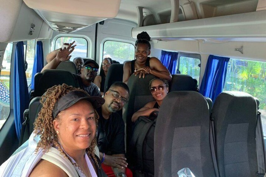 A group of people seated inside a vehicle with blue curtains and a window. 4