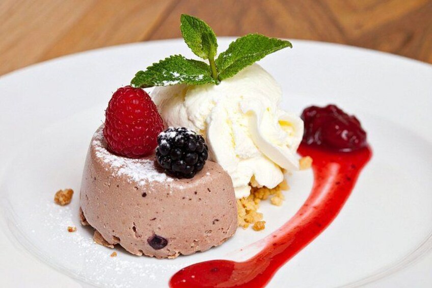 A dessert with a scoop of ice cream, berries, and a dusting of powdered sugar on a plate. 3