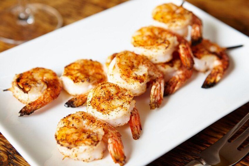 A white rectangular plate with grilled shrimp skewers. 2