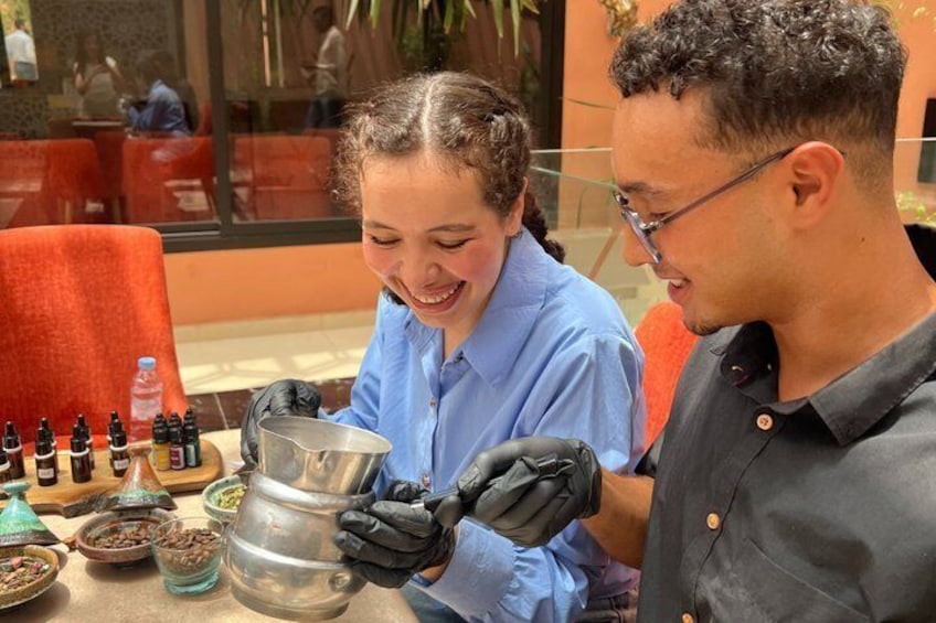 A person in a blue shirt and black gloves handling a large metal pot, with various spices and bottles on the table. 5