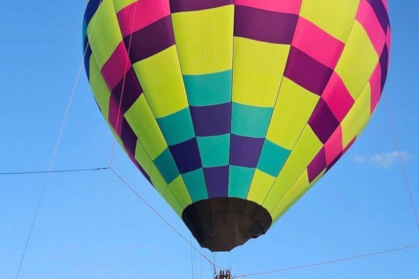 A colorful hot air balloon with a checkered pattern against a clear blue sky. 3