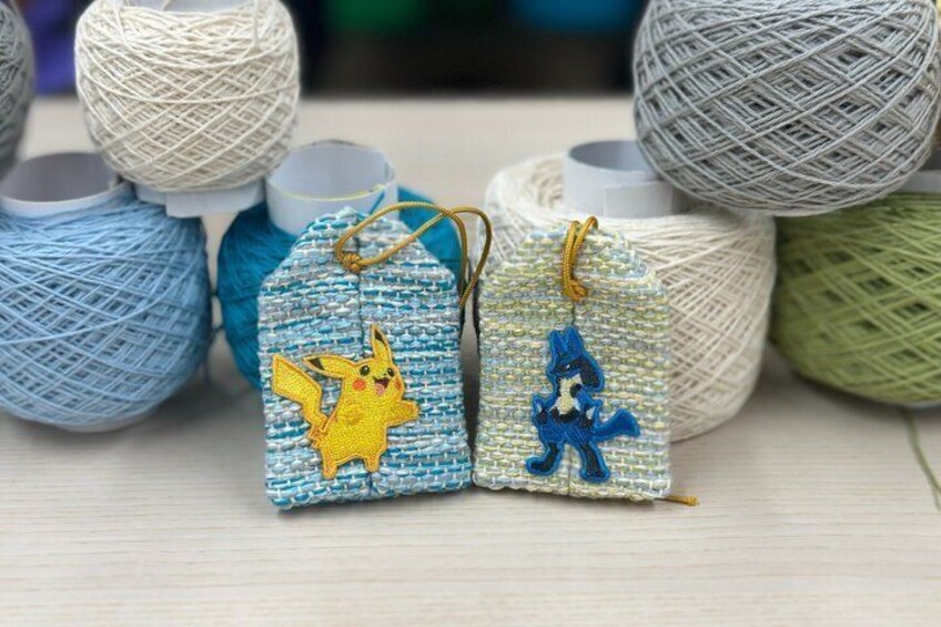 Two small fabric tags with Pokemon characters, surrounded by yarn balls. 3