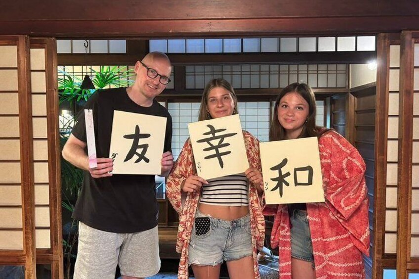 Tre personer håller upp skyltar med japanska tecken. 5