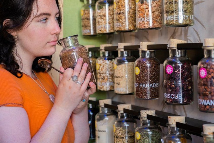 A person holding a jar labeled 'OF PARADISE' in a store with shelves of other labeled jars. 3