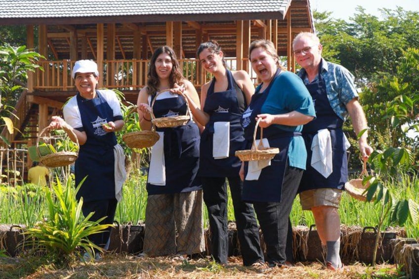A group of people holding baskets in a garden with a wooden structure in the background. 2
