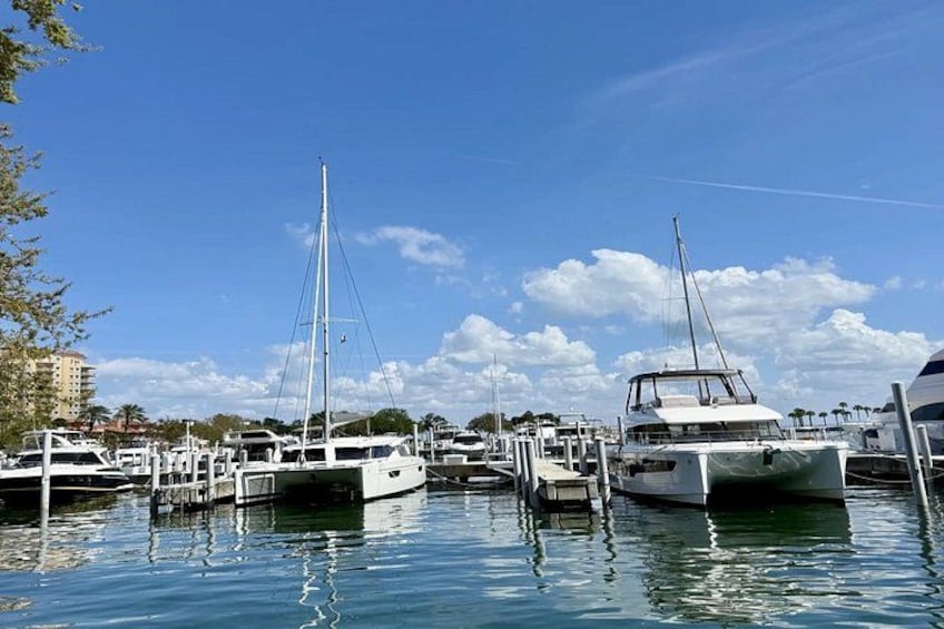 A marina with several sailboats docked, calm water, and a clear sky. 3
