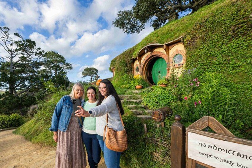 Een tuin in Hobbiton-stijl met Hobbit-huizen, een pad van aarde en een bord met de tekst 'geen toegang, tenzij voor feestelijke zaken'. 3