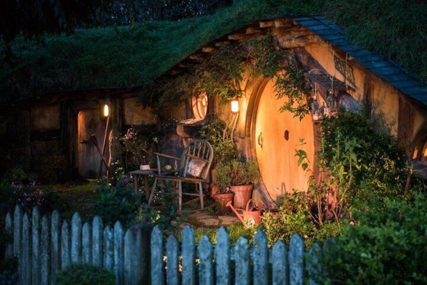 A Hobbit-style house with a thatched roof, a wooden door, and a chair outside. 5
