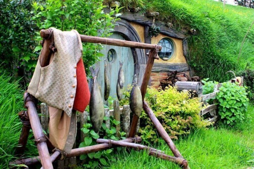 A Hobbit-style house with a round door and a window, surrounded by lush greenery. 1