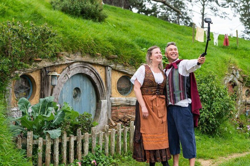 Ein Hobbit-Haus, eine Person macht ein Selfie und ein Holzzaun. 3