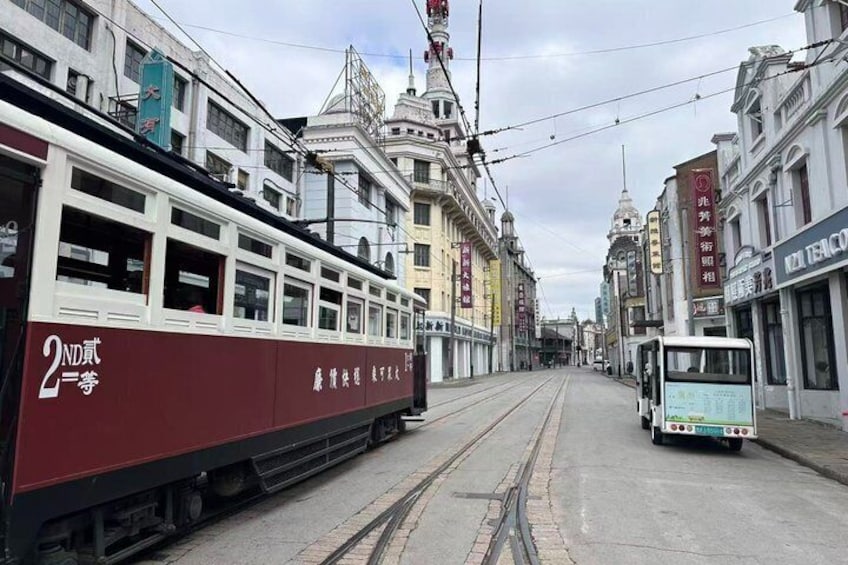 A tram on a track, buildings on either side, and a street in a city. 5