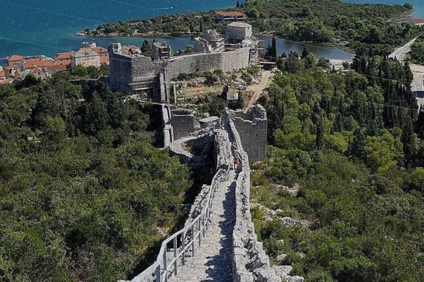 A historical stone wall, a fortified structure, and a body of water. 5