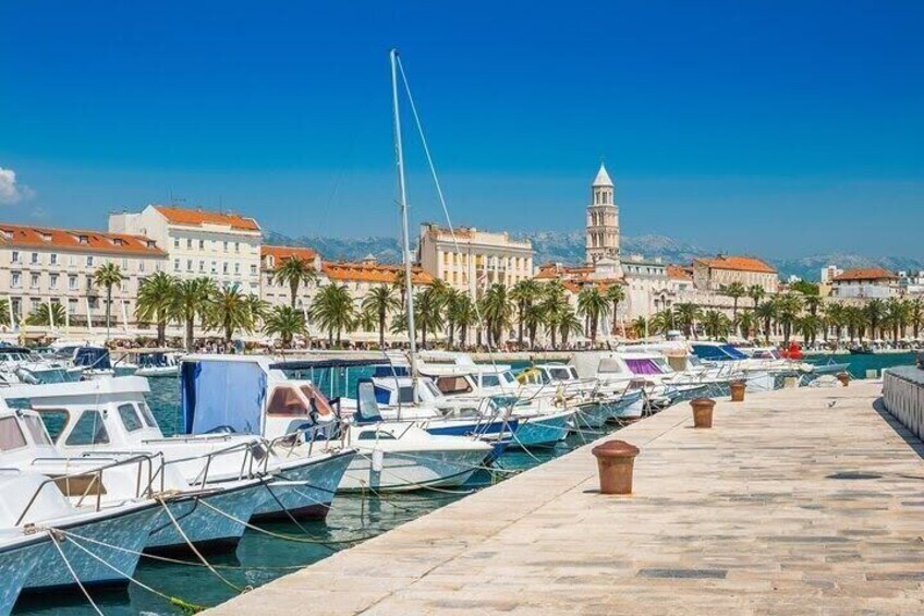 A marina with boats docked, a clear blue sky, and a tower in the background. 1