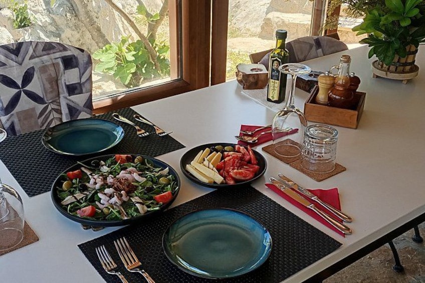 A dining table set with plates, cutlery, and a bottle of olive oil. 4