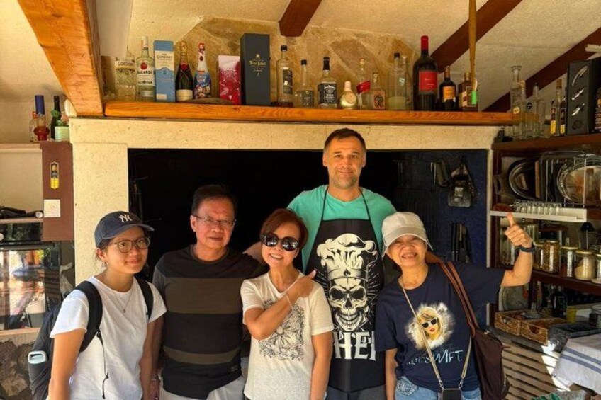 A group of people in a bar with shelves of bottles and kitchen equipment. 2