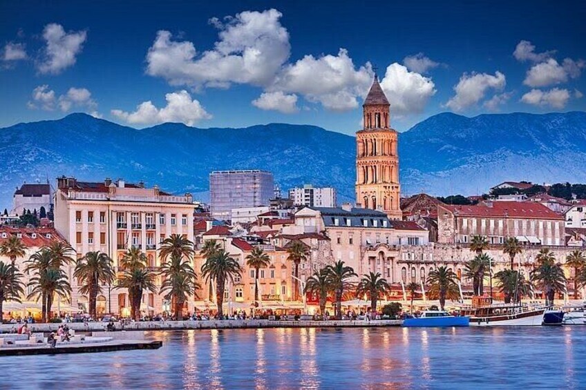 A coastal cityscape with a prominent tower, palm trees, and a body of water reflecting the buildings. 2