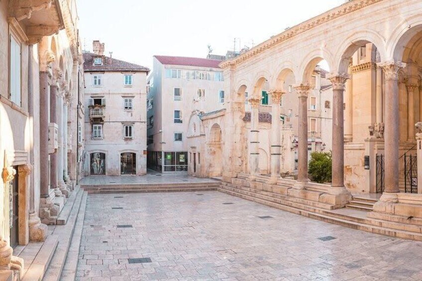 Un patio histórico con arquitectura clásica, incluyendo arcos y columnas, y suelo empedrado. 3