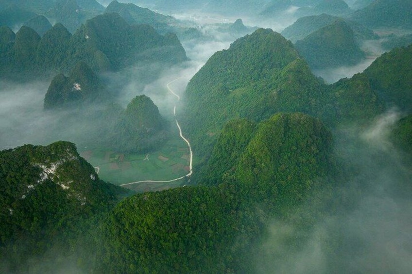 A winding road through a mountainous landscape with lush greenery and mist. 5