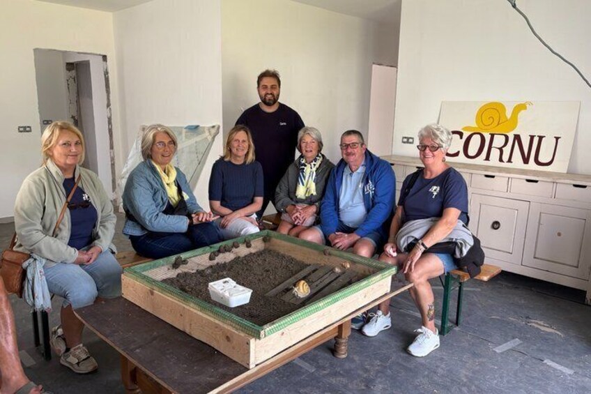 A group of people sitting around a table with a small garden setup. 2