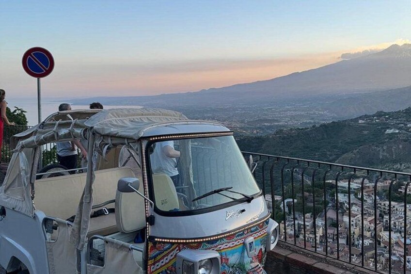 A covered vehicle with a colorful design parked on a balcony overlooking a cityscape. 4
