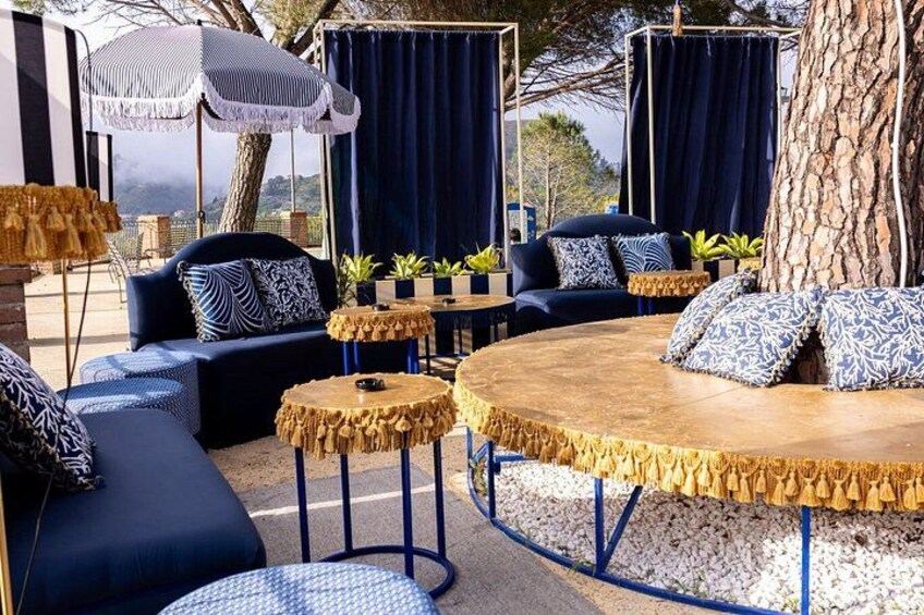 A lounge area with blue sofas, round tables, and a large tree. 3