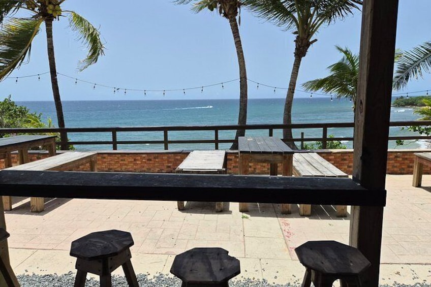 A wooden deck with benches overlooking a beach with palm trees and the ocean. 3