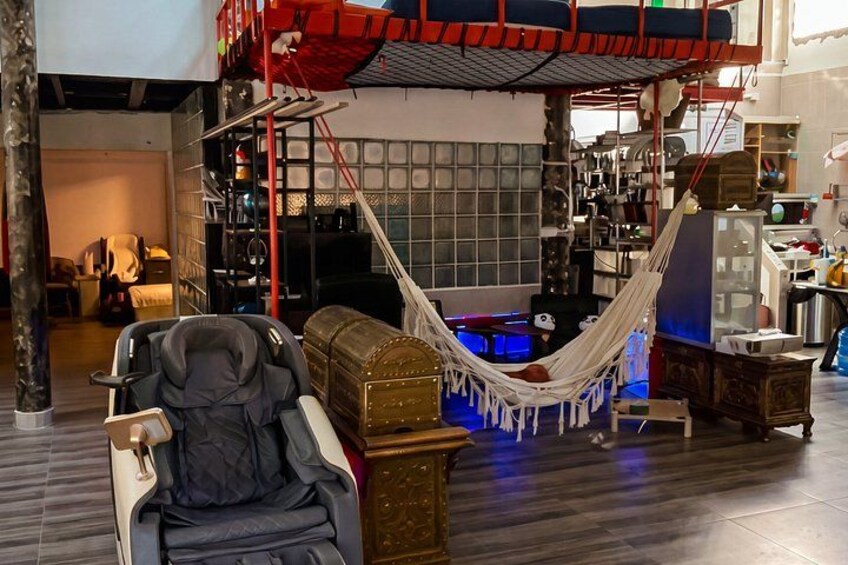 A hammock, a chair, and a couch in a room with shelves and a red ladder. 3