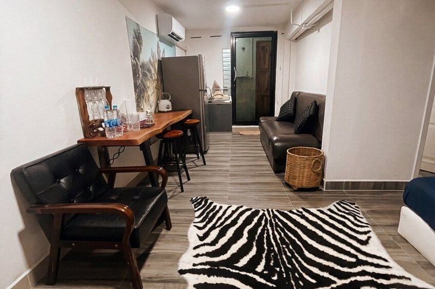 A modern living room with a zebra rug, a sofa, a dining table with chairs, and a kitchen area in the background. 2