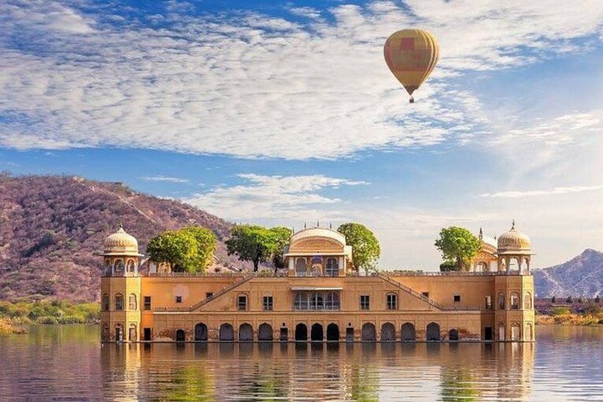 A historic building with domes and arches, surrounded by water and mountains. 1