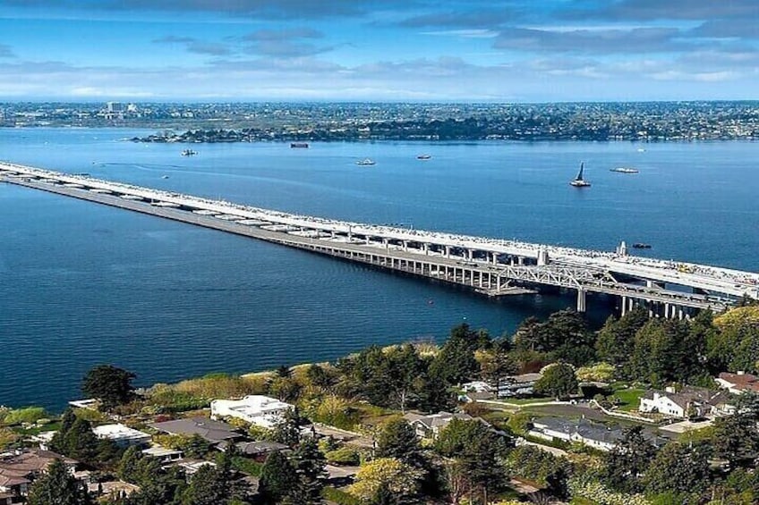 A bridge over a large body of water with boats, a cityscape in the background, and residential areas in the foreground. 2