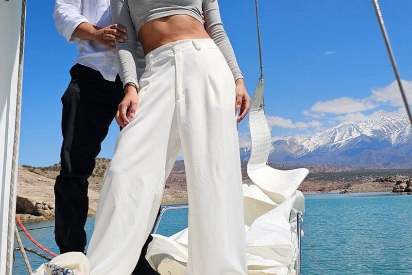 A person in white pants standing on a boat with a mountainous landscape in the background. 3