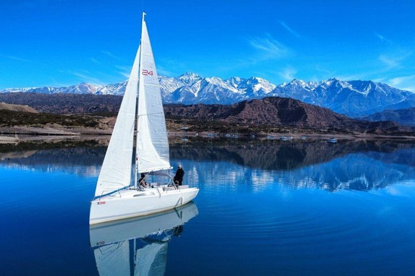 A sailboat on calm water with a mountainous landscape in the background. 1