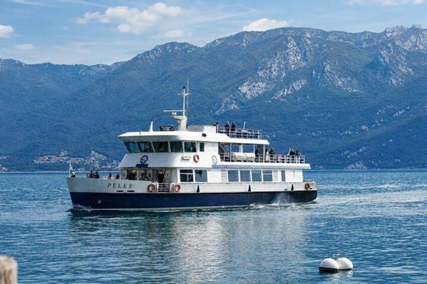A boat named 'PELER' on calm water with mountains in the background. 2