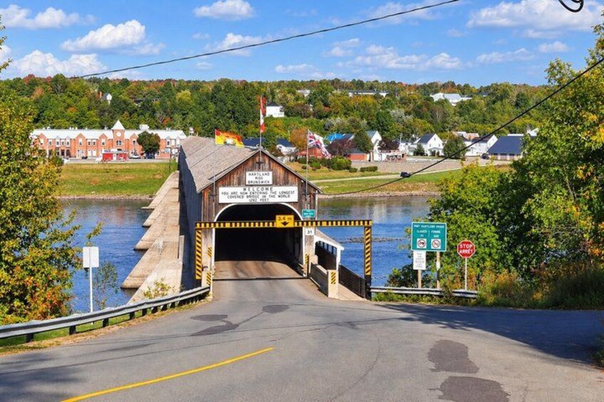 A covered bridge over a river with a sign indicating it is a historic site. 4
