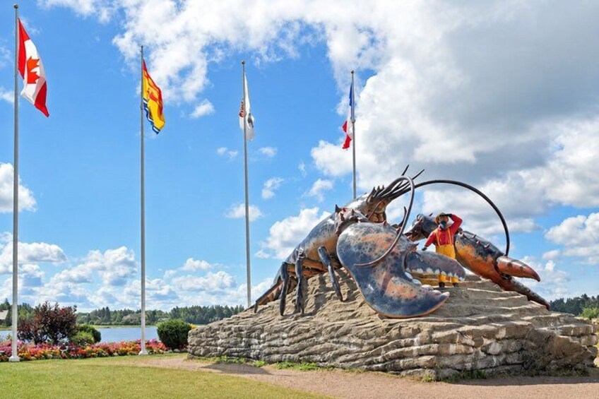 A large lobster sculpture on a rock with multiple flags in the background. 3