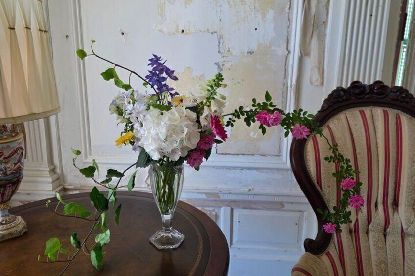 A vase with flowers on a table, a lamp, and a chair with a striped cushion. 3