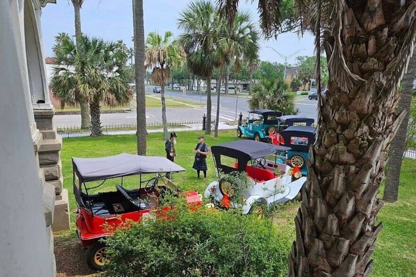 A red and white horse-drawn carriage parked on a grassy area with palm trees in the background. 5