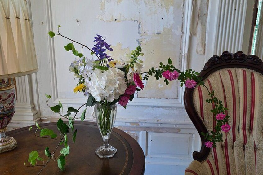 A vase with flowers on a table, a lamp, and a chair with a striped pattern. 2