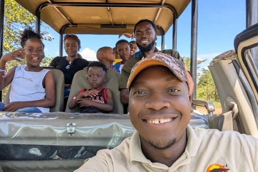 A group of people inside a vehicle with a clear sky and trees in the background. 3