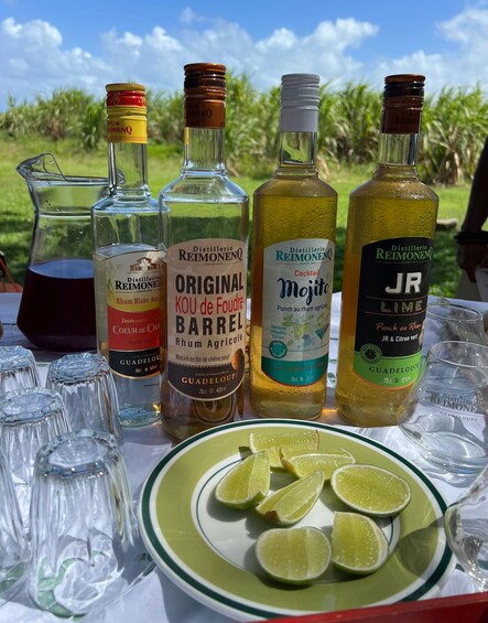 A table with various bottles of rum and a pitcher of red liquid, surrounded by empty glasses and lime slices. 4