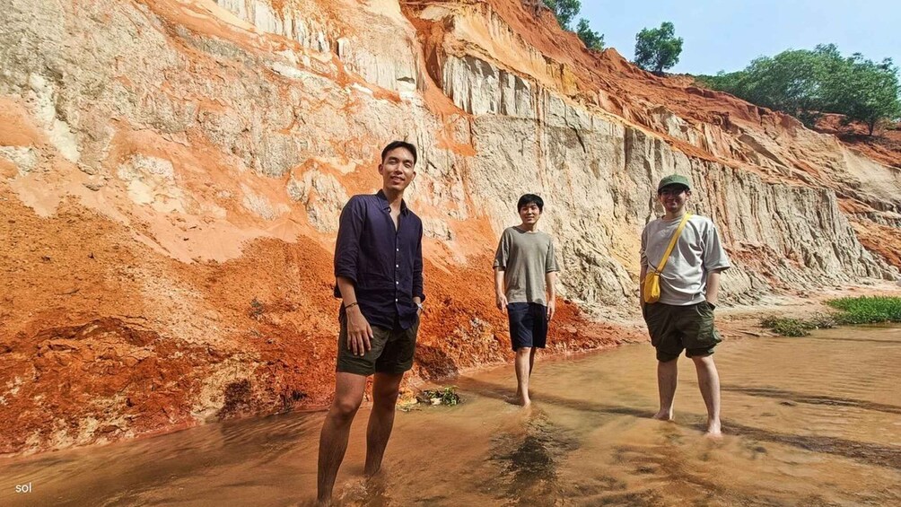 Three individuals standing in front of a red and white layered rock formation. 1