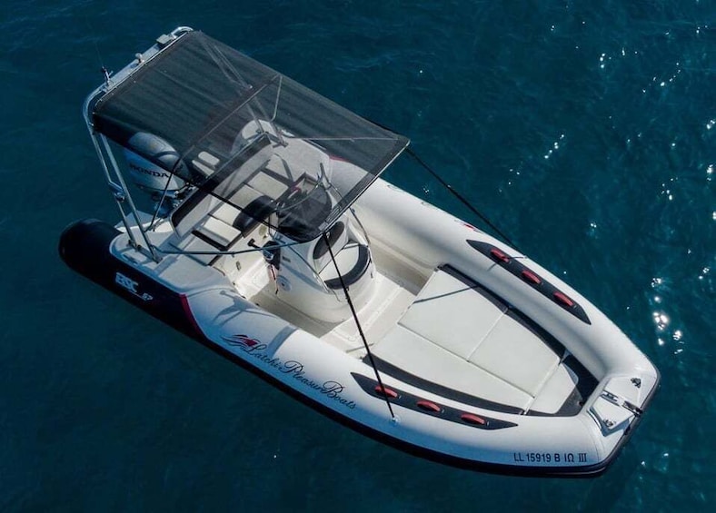 A white motorboat with a canopy, a Honda outboard motor, and the text 'Ratchiki Pleasure Boats' on the side. 1