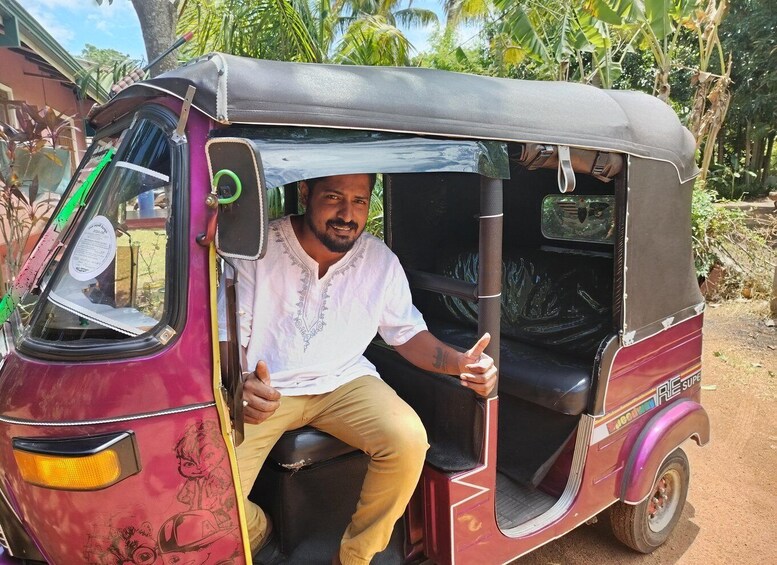 Un homme est assis dans un auto-rickshaw rouge avec un toit noir, garé à l’extérieur, avec de la verdure en arrière-plan. 4