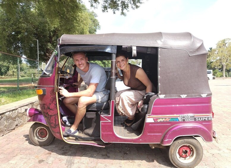 Un homme et une femme sont assis dans un auto-rickshaw violet sur lequel on peut lire les mots « RIE SUPER » sur le côté. 5