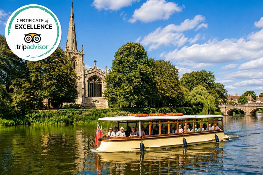 A riverboat tour with passengers, a historic church, and a bridge in the background. 2