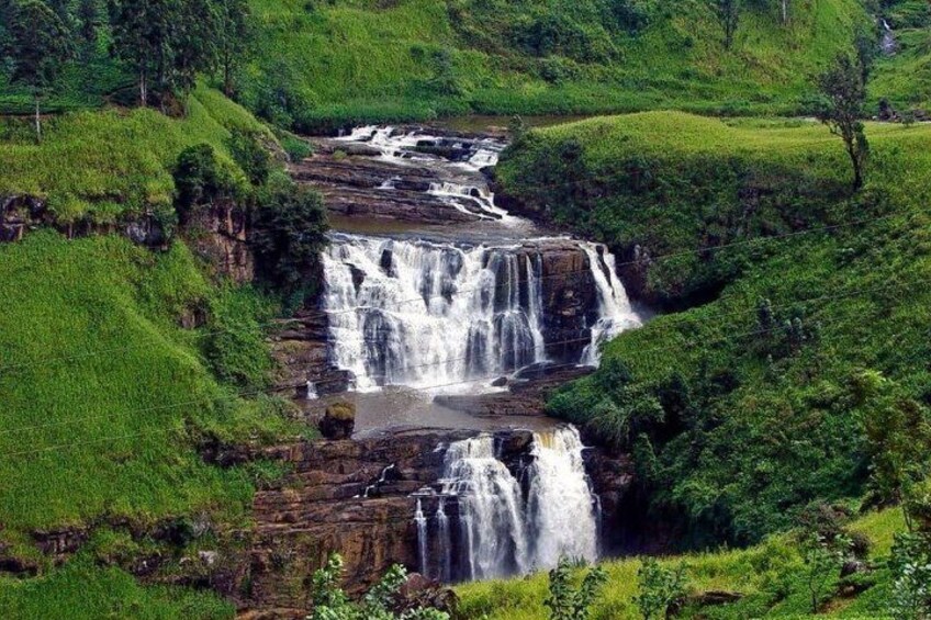 A multi-tiered waterfall surrounded by lush green hills. 3