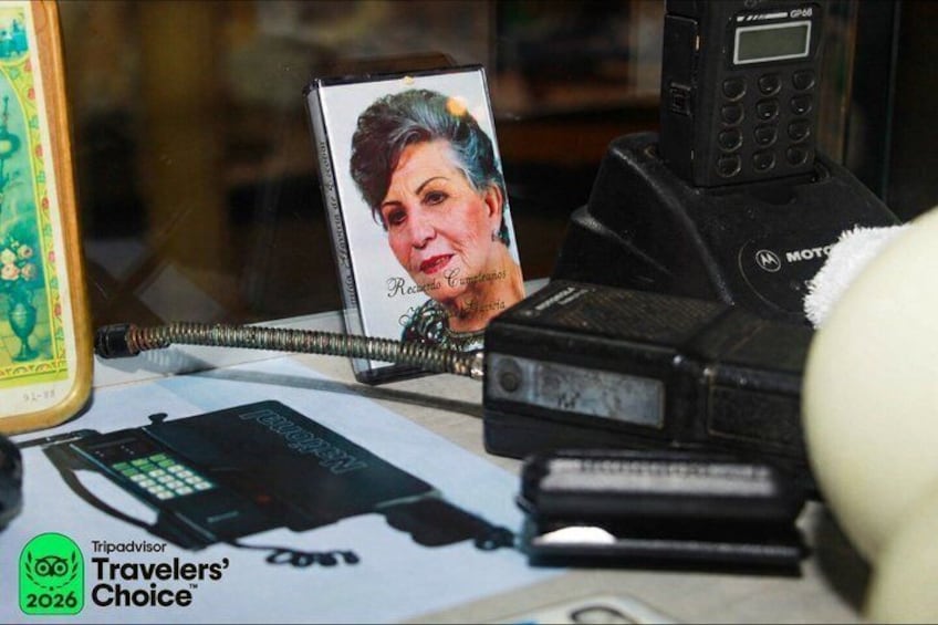 A desk with a Motorola phone, a TripAdvisor 2026 Traveler's Choice badge, a smartphone, and a photo frame. 1