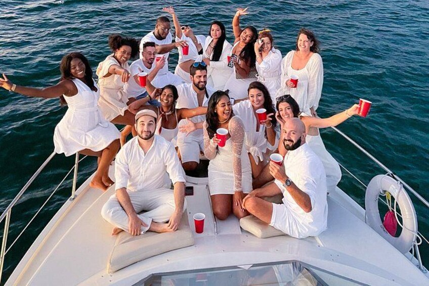 A group of people on a boat, wearing white, with red cups. 2