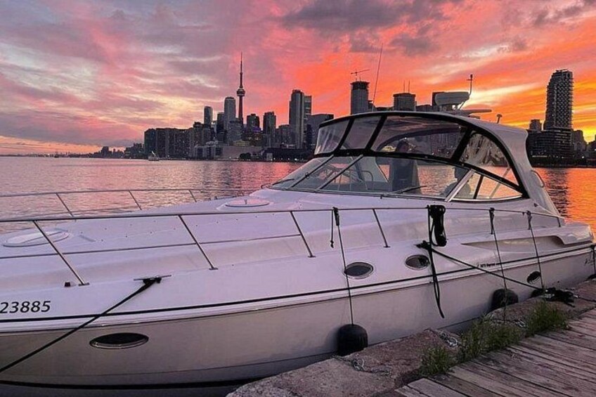 A white boat with the number 23885 docked at a wooden pier with a city skyline in the background. 3