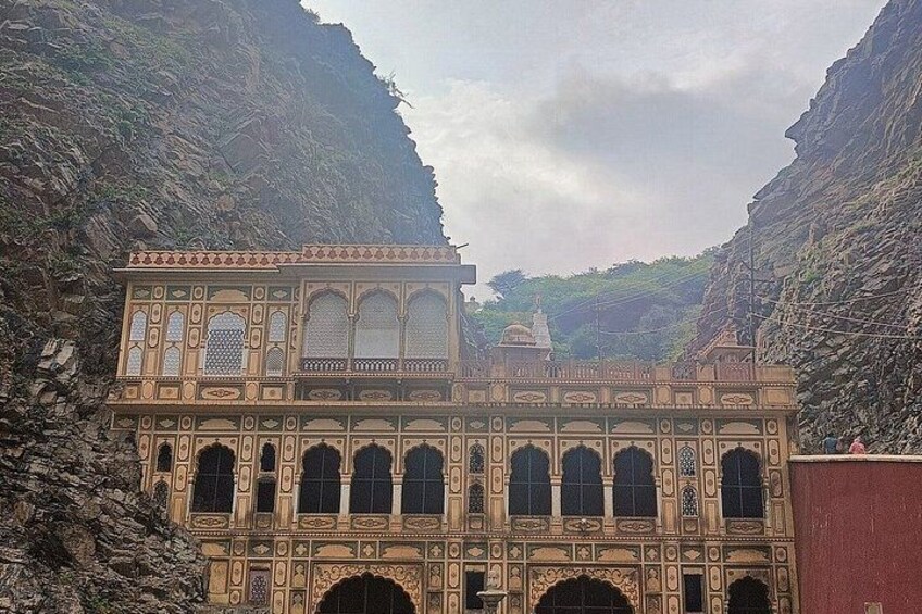 A historical building with intricate architecture, set against a rocky cliff backdrop. 4